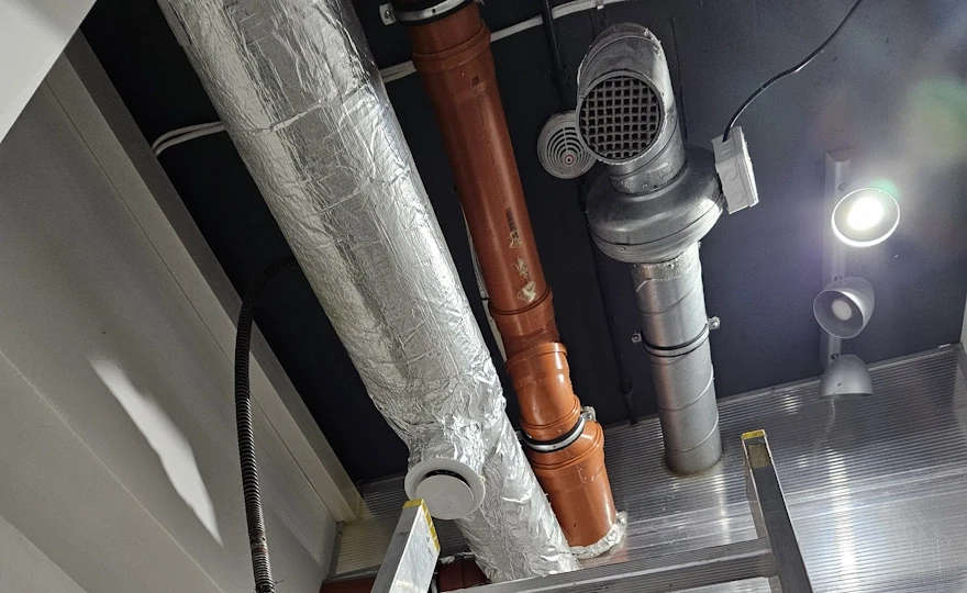 Pion kanalizacyjny i instalacja wentylacyjna restauracji — widok z drabiny