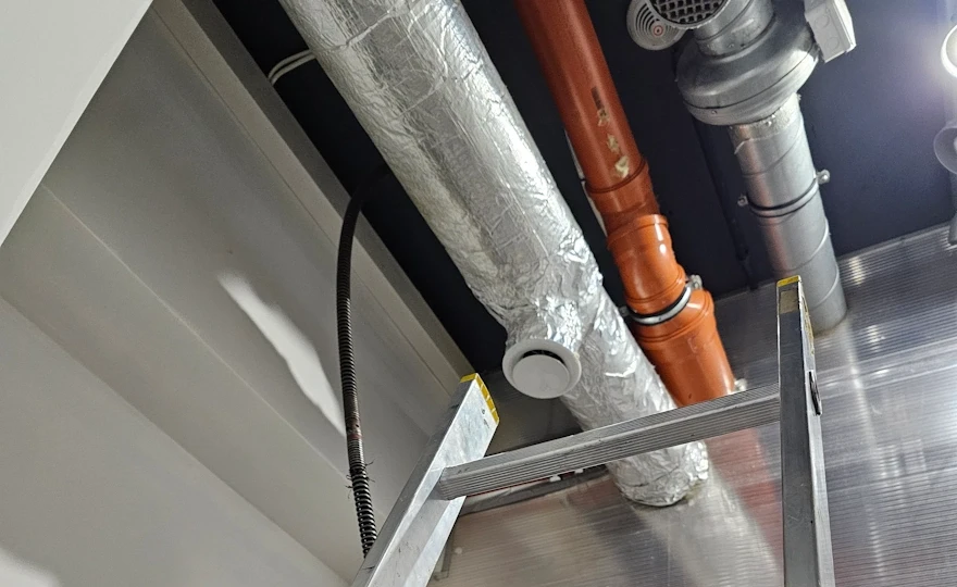 Praca na drabinie przy czyszczeniu pionu kanalizacyjnego DN 200 w restauracji